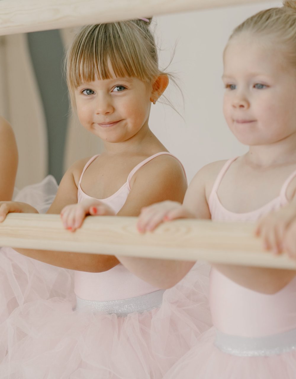 Cute little ballerinas in pink ballet costume. Children in a pointe shoes is dancing in the room. Kid in dance class.